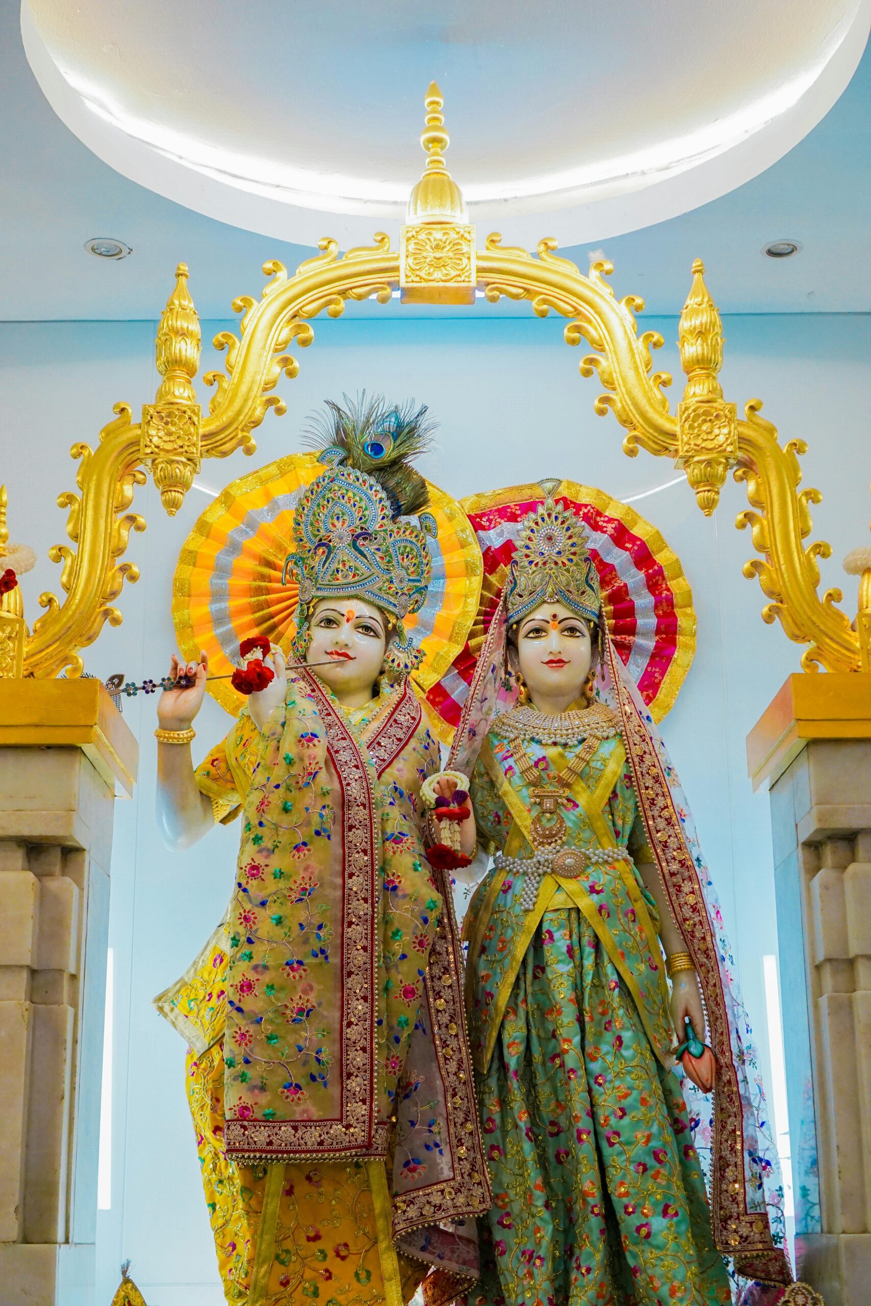 Statues of Krishna and Radha in a Thai temple showcasing vibrant traditional art.